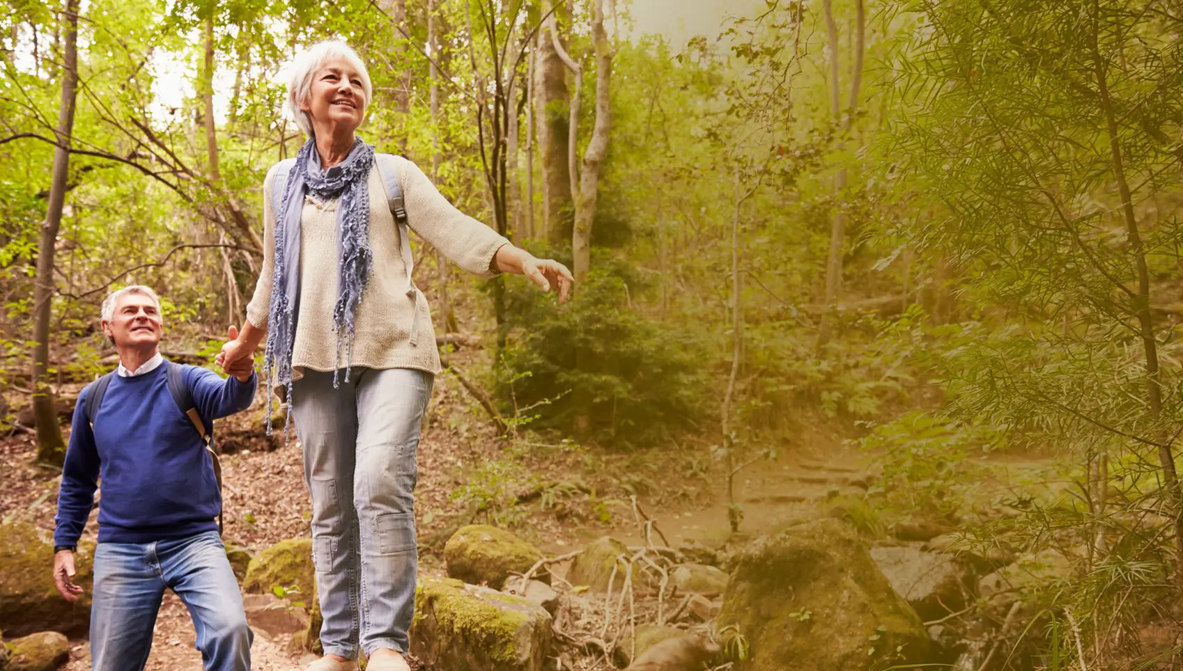 A woman standing on top of a hill near trees.