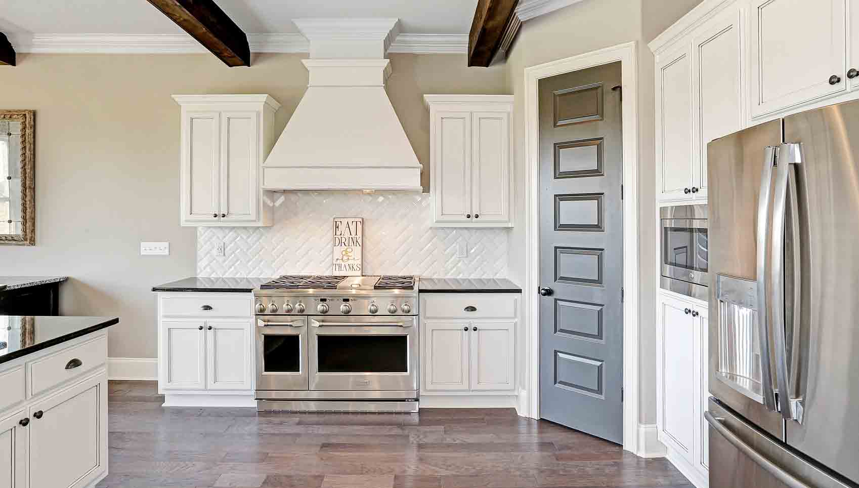 A kitchen with white cabinets and wood floors.