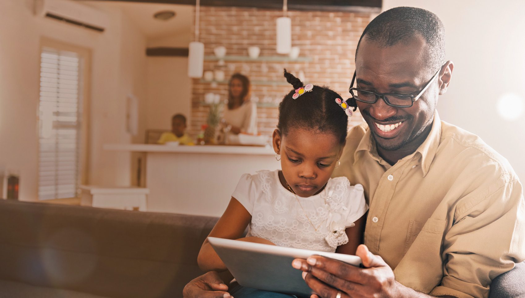 A man and his daughter are looking at an ipad.